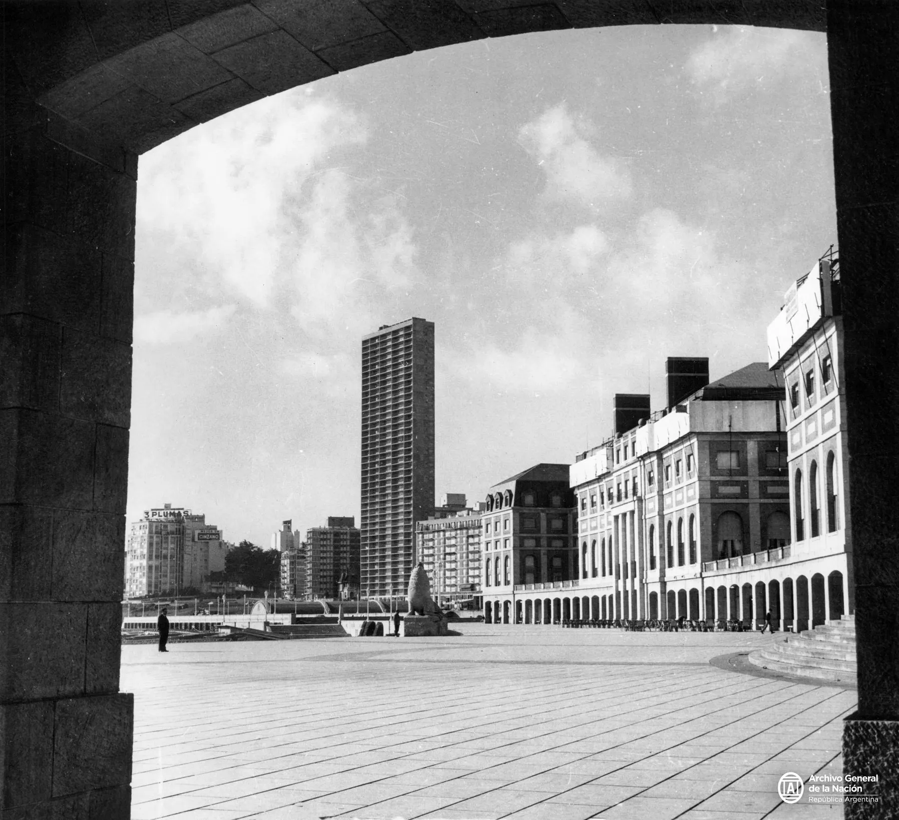 La Rambla de Mar del Plata en 1969, vue en noir et blanc sous une arcade : une vaste esplanade et des immeubles