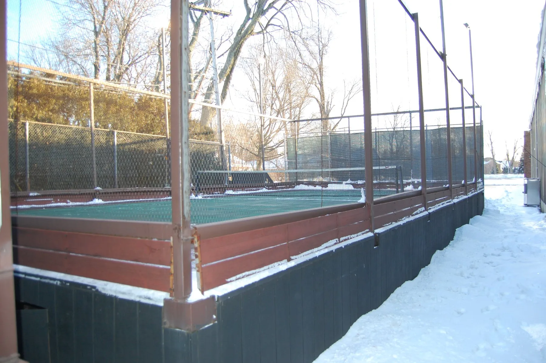Un terrain de platform tennis surélevé et entouré de grillage, sous la neige, dans le Michigan