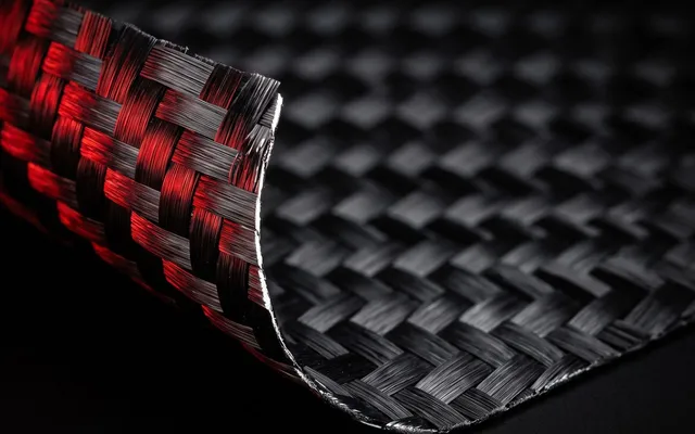Macro du tissage carbone d'une raquette de padel SCUD en lumière rasante rouge, damiers du tissu nettement visibles