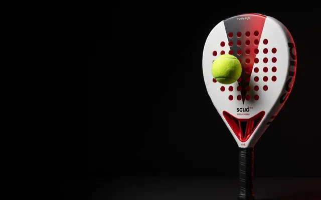 The SCUD White S3 racket standing in the dark, a padel ball motionless in front of the centre of the white face
