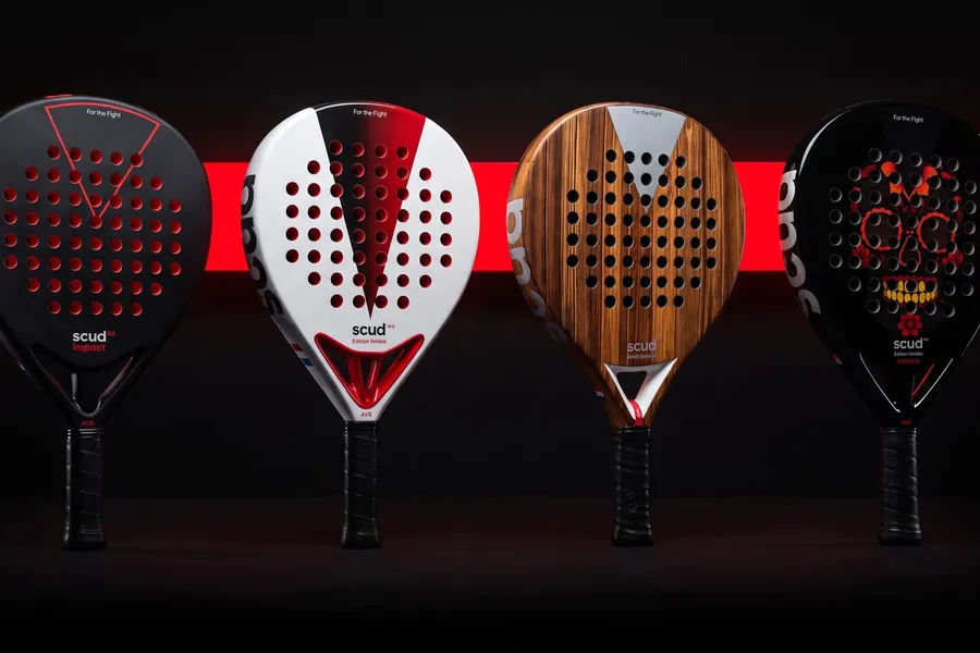 The four SCUD rackets lined up against a black wall crossed by a red line of light: Black Impact B3, White S3, Wood S1 and Mexique M1