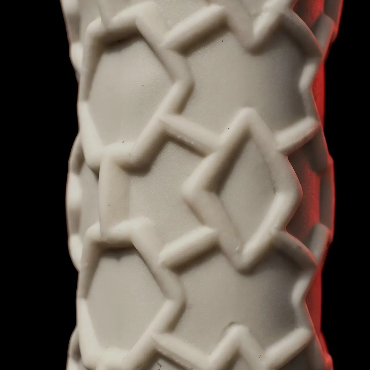 Macro du manche en silicone alvéolé d'une raquette SCUD avant la pose du grip : un relief d'étoiles et de losanges