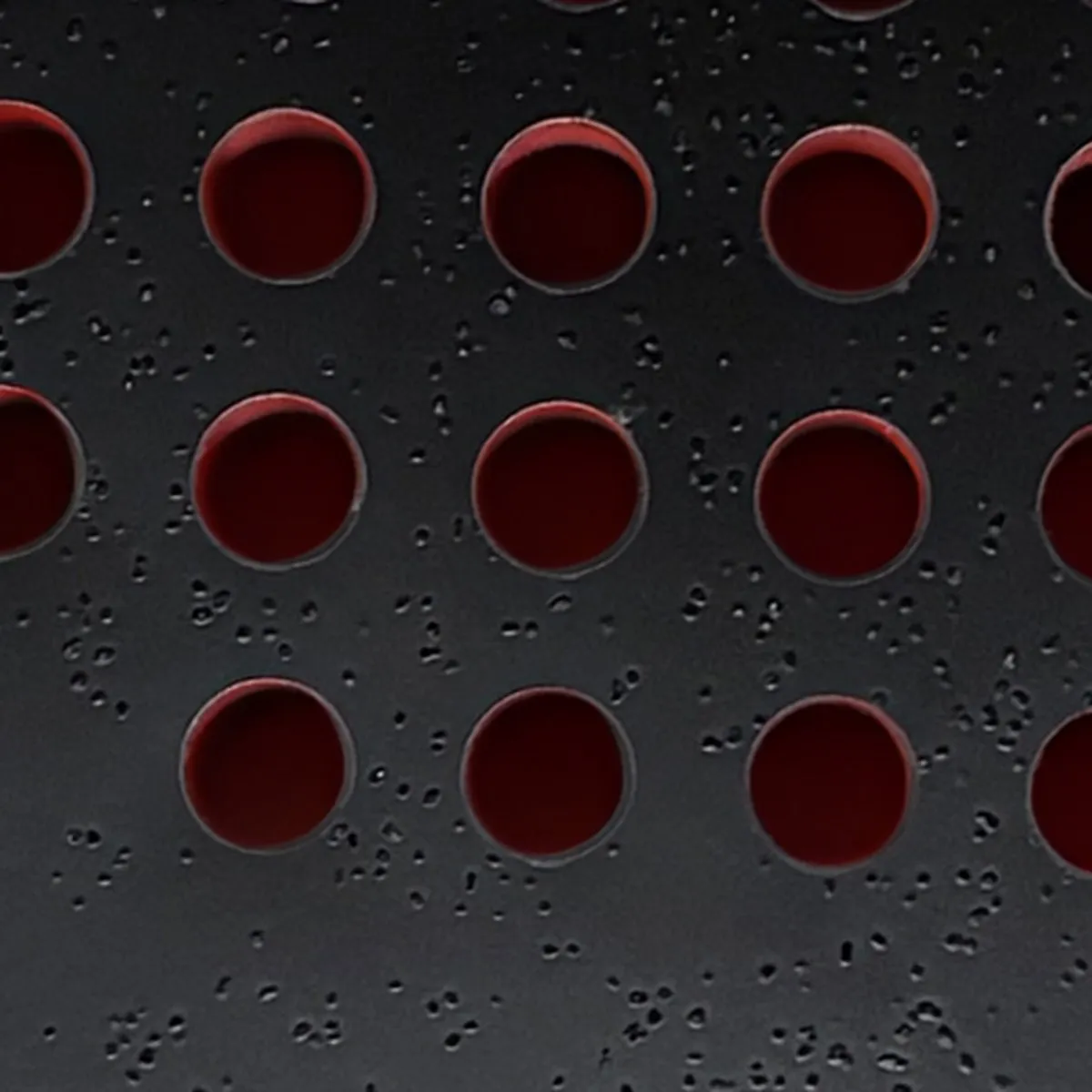 Grande plano da face da SCUD Black Impact B3: grão de sílica e perfurações vermelhas