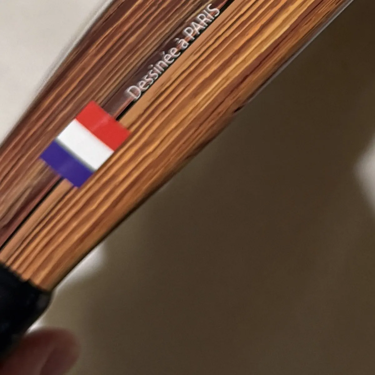 Grande plano do aro da SCUD Wood W1: acabamento em madeira, bandeira francesa e a inscrição “Dessinée à Paris”