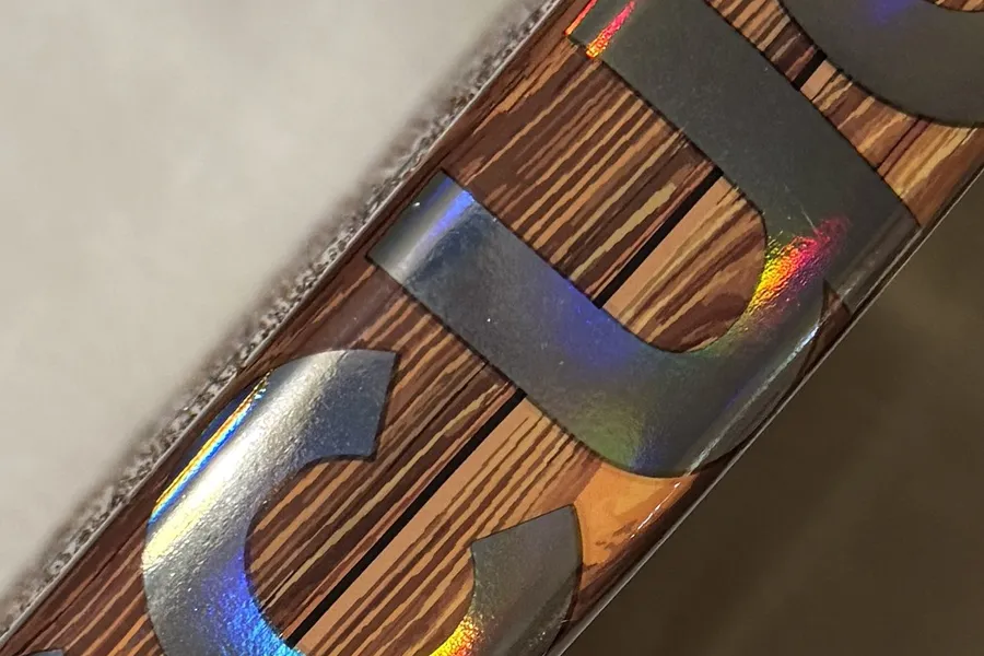Grande plano do aro da SCUD Wood W1: acabamento em madeira e letras holográficas