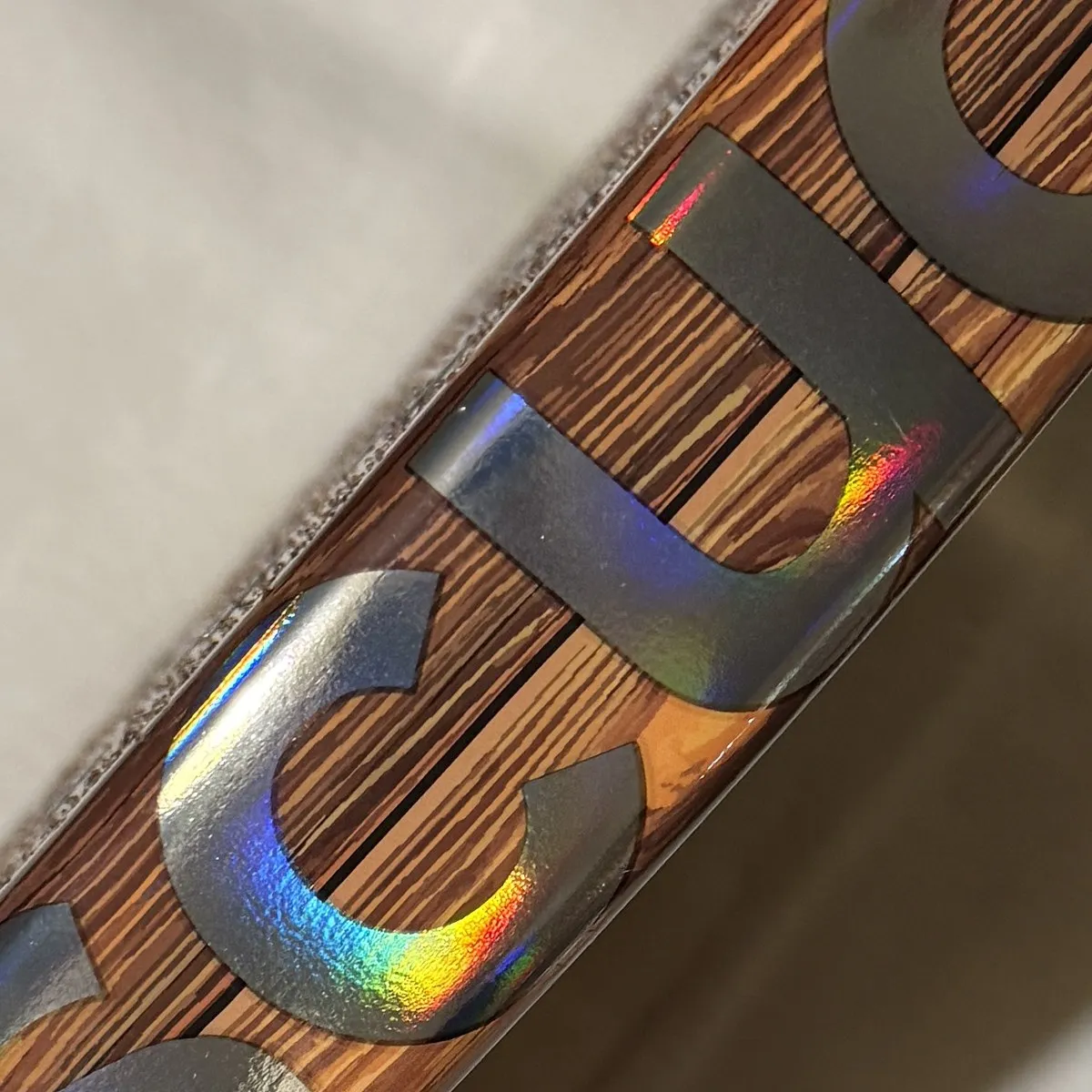 Grande plano do aro da SCUD Wood W1: acabamento em madeira e letras holográficas