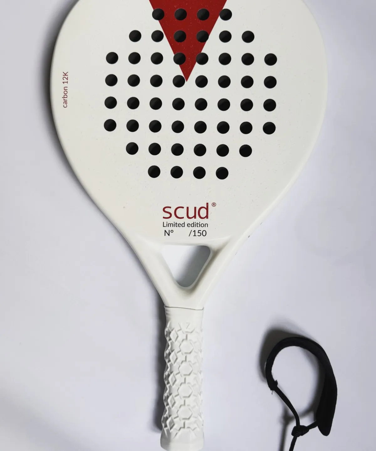 Raquette de padel SCUD blanche photographiée à plat sur fond blanc : le triangle rouge en tête de tamis, la mention carbon 12K sur le bord et le logo scud Limited edition sous le cœur