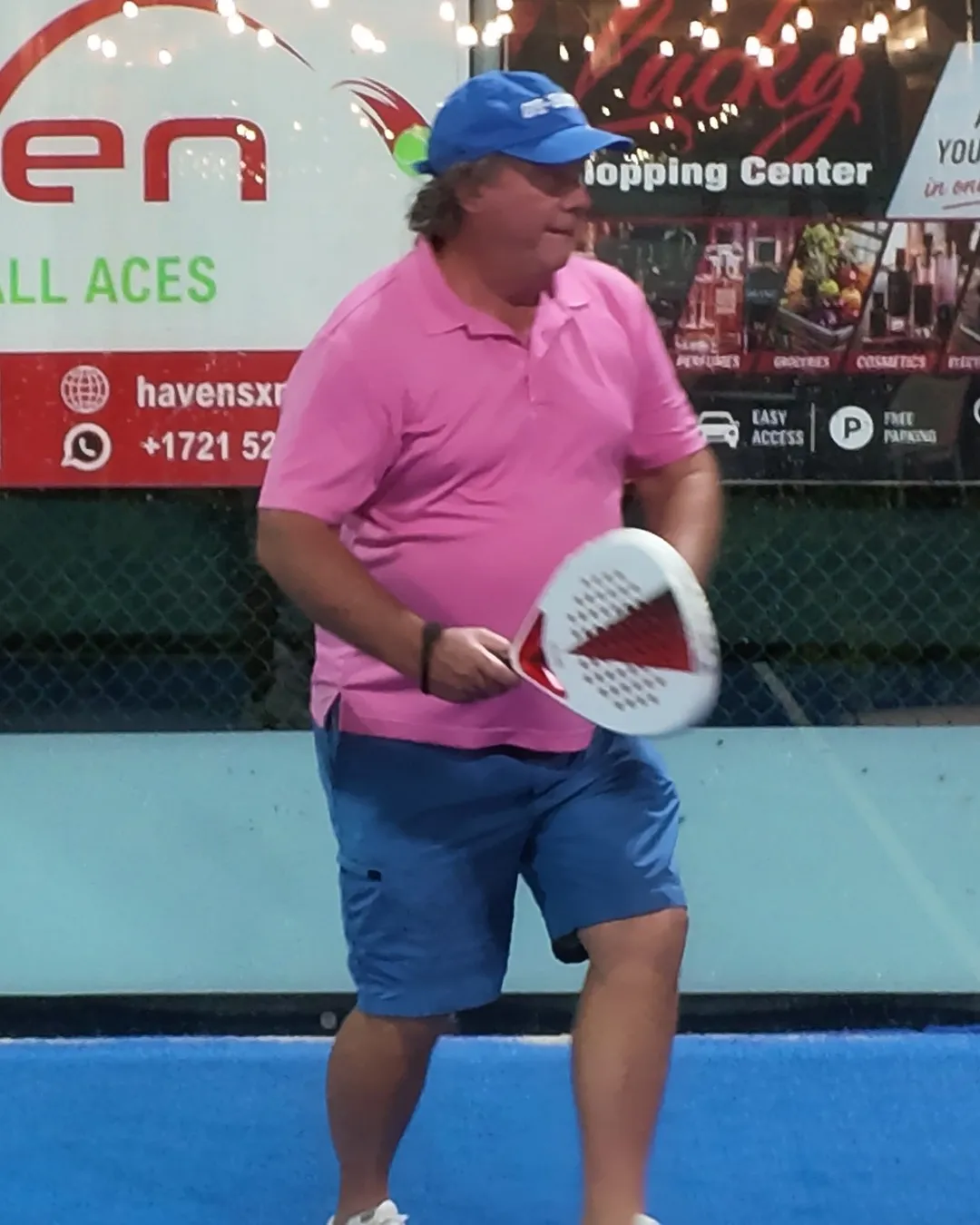 Le même joueur en polo rose se replace, raquette SCUD White levée